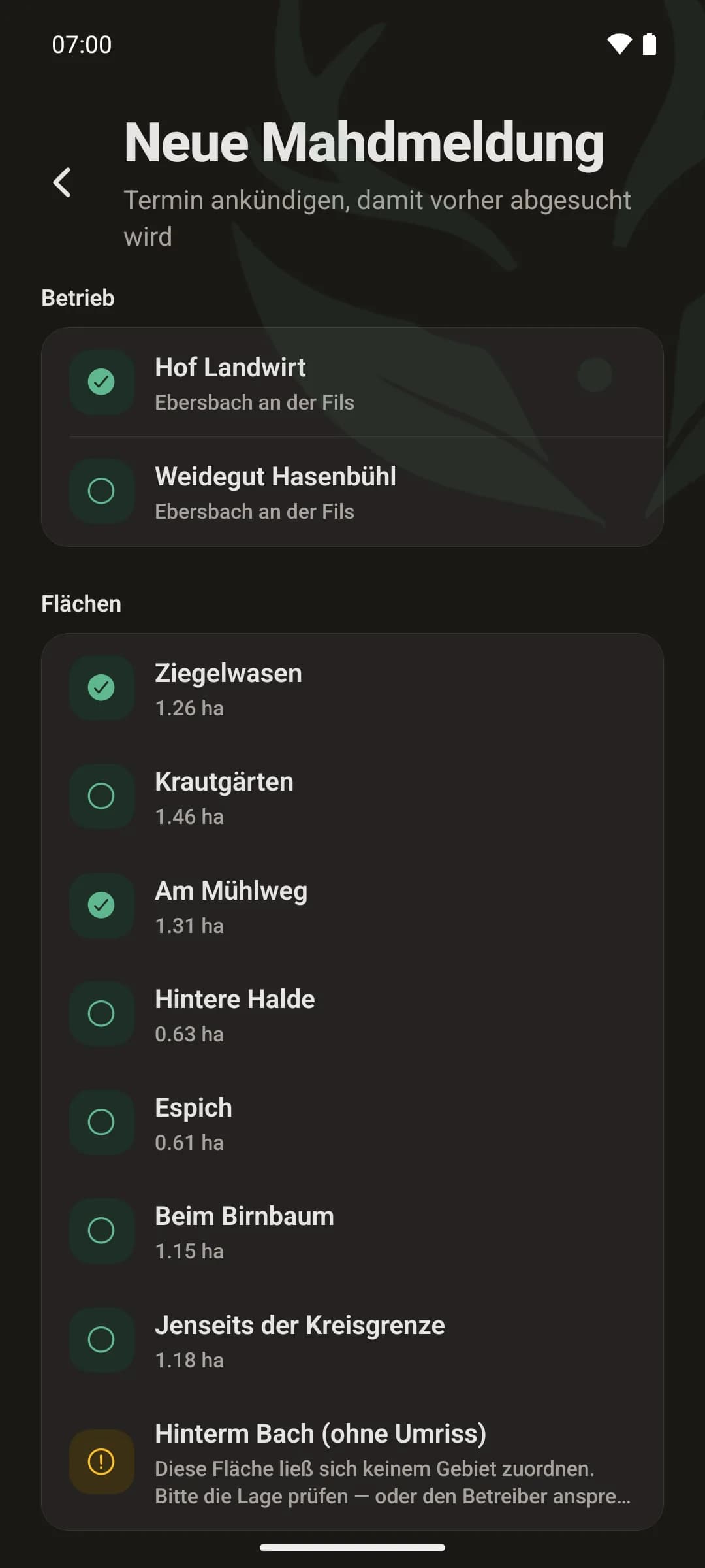 Neue Mahdmeldung in der App: Auswahl des Betriebs und darunter die eigenen Flächen mit Hektarangabe, zwei davon ausgewählt — kein Suchen nach Flurstücksnummern